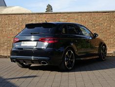 a black car parked in front of a brick wall