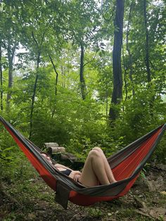 a woman laying in a hammock with her legs crossed and head resting on the ground