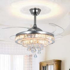 a ceiling fan with crystal chandelier hanging from it's blades in a living room