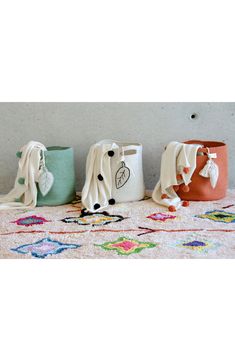 three different colored vases sitting on top of a white table cloth covered floor next to each other