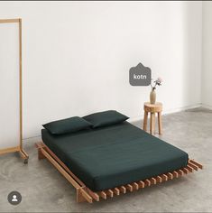 a bed sitting in the middle of a room next to a table with a vase on it