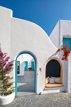 a white building with blue doors and flowers on the outside