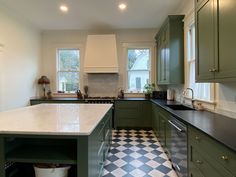 a large kitchen with green cabinets and checkered flooring on the floor, along with an island in the middle