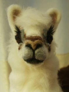 an alpaca stuffed animal sitting on top of a bed