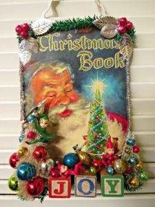 an old fashioned christmas book is hanging on the wall with ornaments and decorations around it