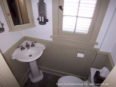 a white sink sitting next to a toilet in a bathroom under a window with shutters