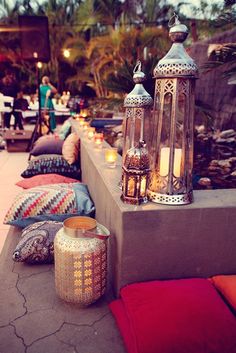 an outdoor seating area with lanterns and pillows