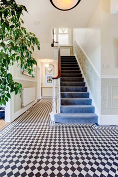 an entryway with black and white checkered flooring next to a staircase leading up to a second story