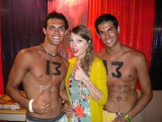 three people with numbers painted on their bodies posing for a photo in front of a red curtain