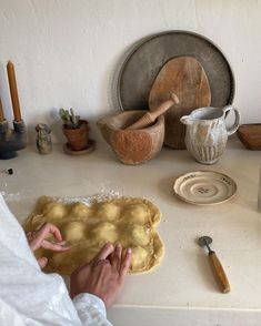 a person is kneading dough on top of a table with other pottery and utensils