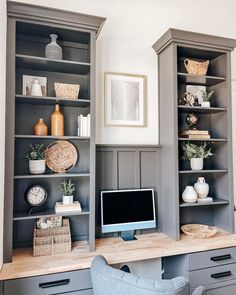 a desk with a computer on top of it in front of gray bookcases