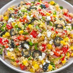 a white bowl filled with rice and vegetables on top of a wooden table next to a fork