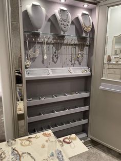 a display case filled with lots of necklaces and jewelry on shelves next to a mirror