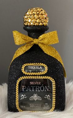 a black bottle with gold sequins and a yellow bow on the top that says tequila silver patron