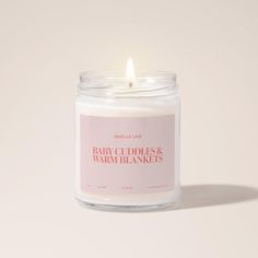 a candle that is sitting on top of a white surface with the words baby clothes and warm blankets printed on it