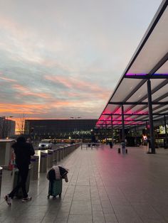 people are walking around an airport terminal at sunset