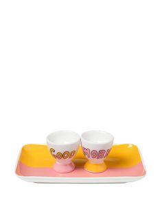 two cups and saucers on a tray with the word good written in pink letters