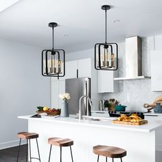 a kitchen with three stools in front of the counter and two lights hanging from the ceiling