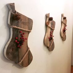 two wooden stockings are hanging on the wall next to each other with red berries attached to them