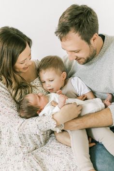 a man, woman and baby are sitting on a bed