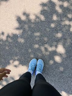 a person with blue shoes standing in front of a tree and holding their hand out