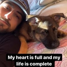 a man laying on top of a bed next to a brown and white dog wearing a hat