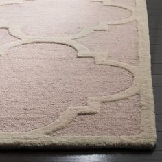 a pink rug with an intricate design on the top and bottom, sitting on a wooden floor