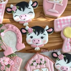 some decorated cookies are sitting on a wooden table with pink and white decorations, such as farm animals