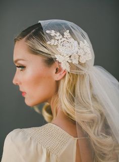 a woman wearing a veil with flowers on it's head and hair comb in her hair