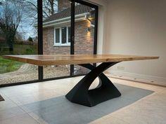 a wooden table sitting on top of a white floor in front of a window with glass doors