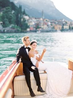 a bride and groom sitting on the back of a boat