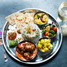 a silver plate topped with different types of food next to a glass of water on a table