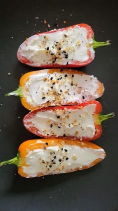 three peppers with cheese and seasoning on them sitting on a black plate, ready to be cooked