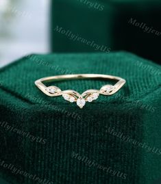 a gold ring with three diamonds on it sitting on top of a green velvet box