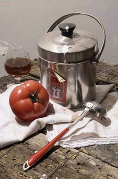 a tomato sitting on top of a white cloth next to a pot and a spoon