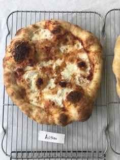 two pizzas sitting on top of cooling racks next to each other