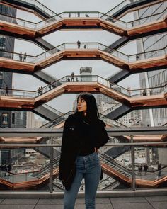 a woman standing in front of a building with lots of glass and wooden balconies