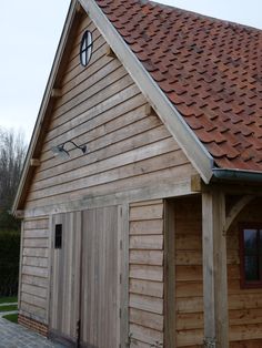 a wooden building with a red roof and brown shingles on it's side