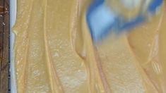 a pan filled with batter sitting on top of a wooden table covered in frosting