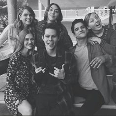 a group of young people sitting on top of a bench smiling and posing for the camera