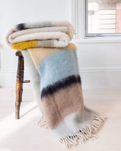 two blankets sitting on top of a chair next to a window