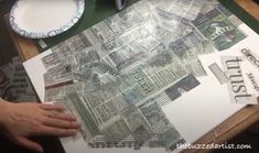 a person is cutting out newspaper pieces on a table with plates and utensils