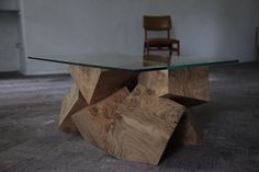 a wooden table with glass top on the floor in front of a chair and wall