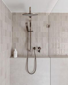 a shower head and hand held shower faucet in a bathroom with tiled walls