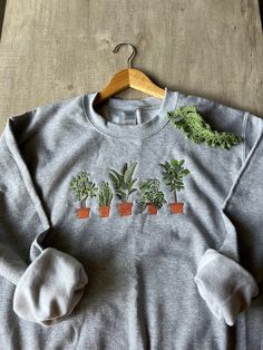 Embroidered Plant Sweater Stunning house plants machine embroidered on a Gildan brand crewneck sweater. The sweater is 50/50 cotton/polyester heavy blend adult unisex. These make a great gifts for yourself or for the plant lover in your life, no watering required (; Please note that all machine embroidery is backed with stabilizer that helps to support the fabric and the stitches. It is a white material inside of the back of the embroidery design, that does get softer with each wash. Care Instructions: Wash the sweater in warm water then tumble dry on low, or hang to dry. Do not iron. Your satisfaction is my drive! Please feel free to message me for questions or potential custom designs/ sizes. Farmers Market Shirt, Plant Parent, Rubber Plant, Embroidery Sweater, Embroidery Hoodie, Botanical Shirt, Father Shirts, Gardening Shirts