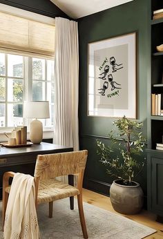 an office with green walls and white drapes on the windowsills, a wooden chair in front of a desk that has a potted plant next to it