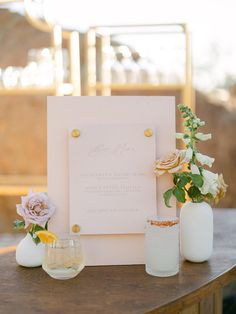 a table topped with vases filled with flowers next to a white sign that says welcome