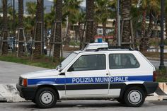 a police car is parked on the side of the road in front of palm trees