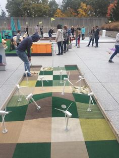 people are playing miniature golf in an open area with many different colored squares on the ground