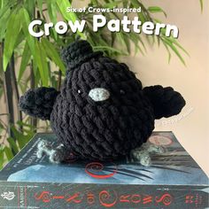 a black crocheted stuffed animal sitting on top of a book with the title crow pattern